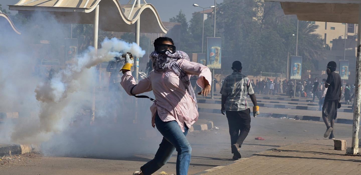 a protestor throwing a smoking object