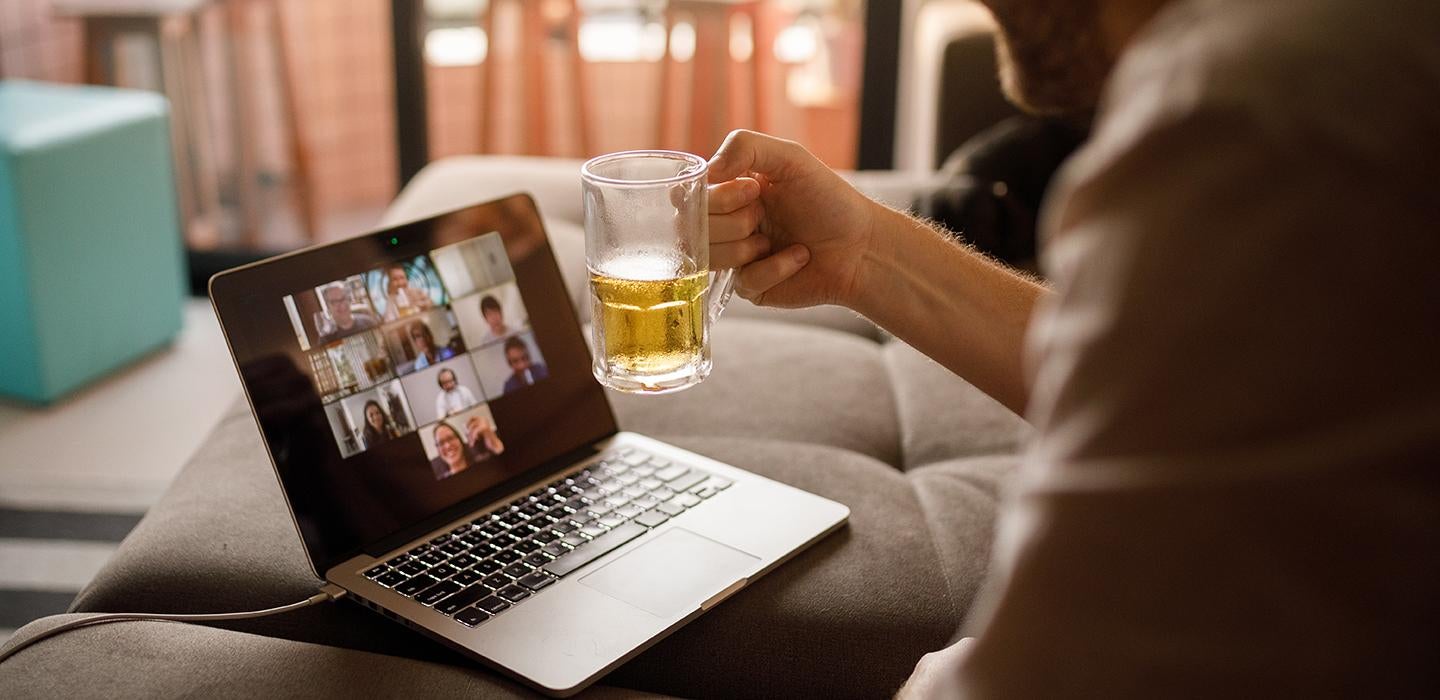 A glass of beer held up in front of a video call meeting