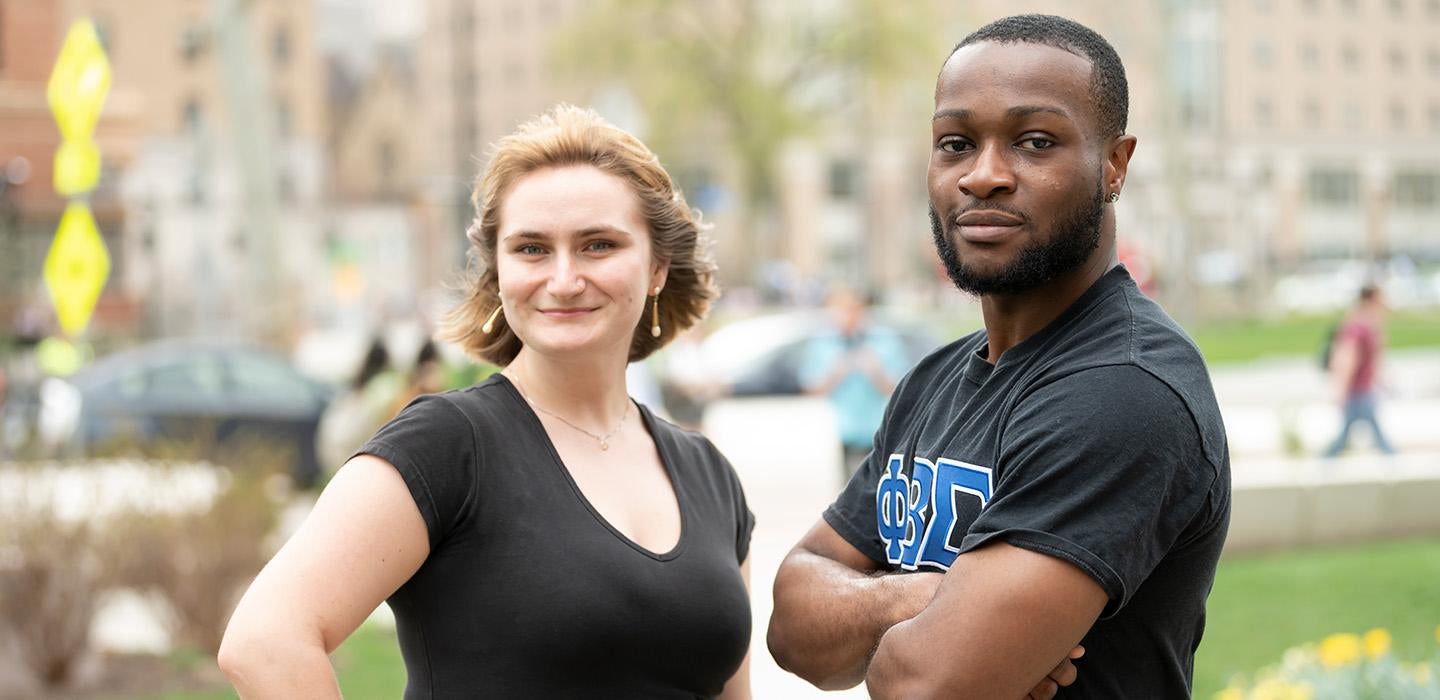 A two people in black shirts pose for a portrait outdoors