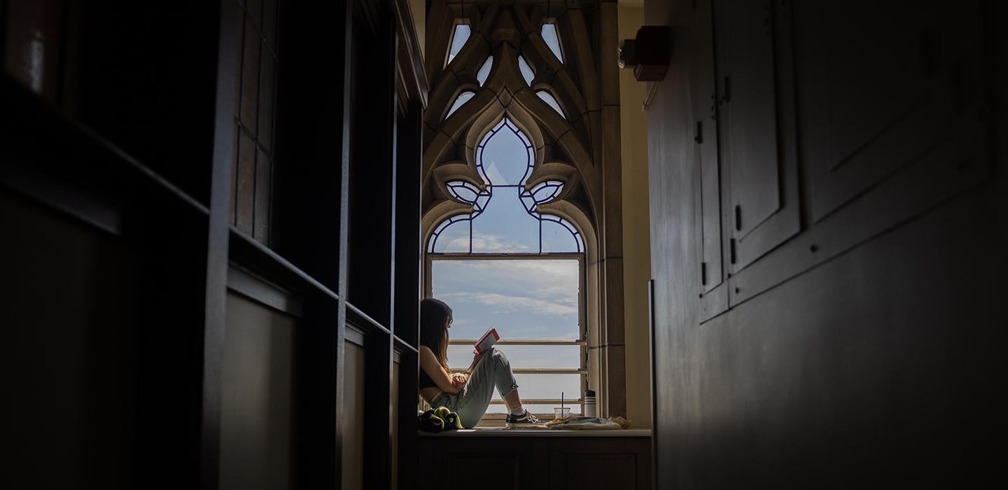 A person reads at a window in the Cathedral of Learning