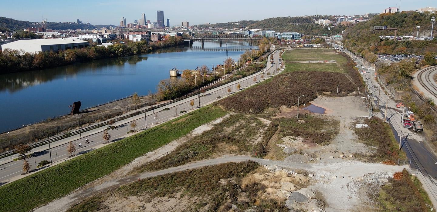 A drone shot of a vacant lot with the Pittsburgh skyline in the background