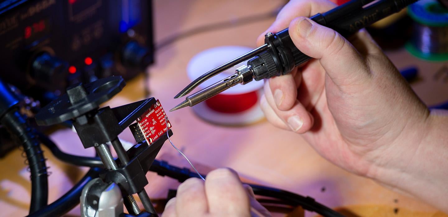 Hands soldering a piece of electronic equipment