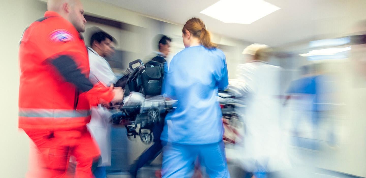 Doctors, nurses and EMS workers rush a stretcher through a hospital
