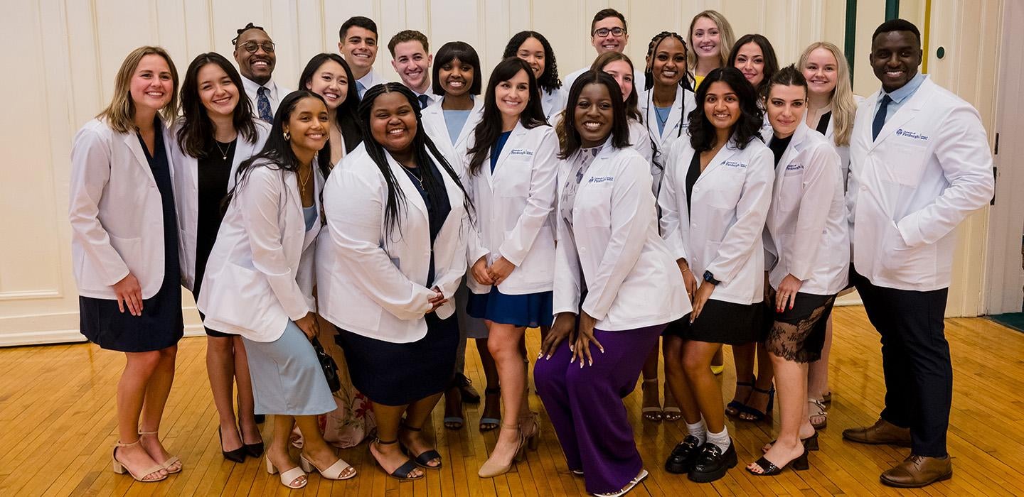 A group of incoming medical students pose in their white coats
