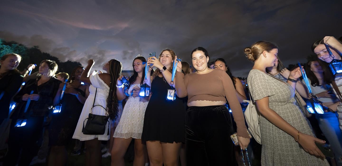 a line of people holding lanterns, taking photos and smiling