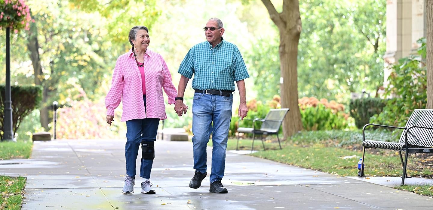 An older couple walks hand-in-hand on Pitt's campus
