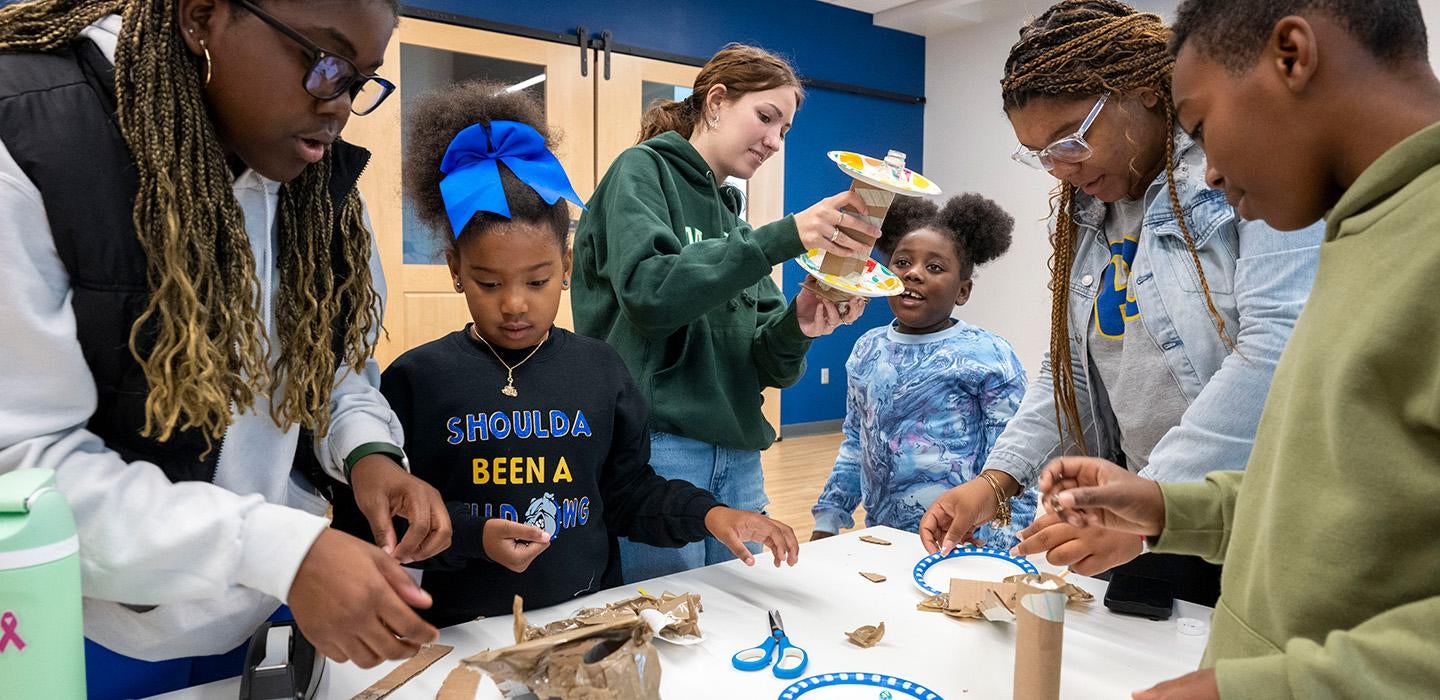 Volunteers help students make crafts with toilet paper holders