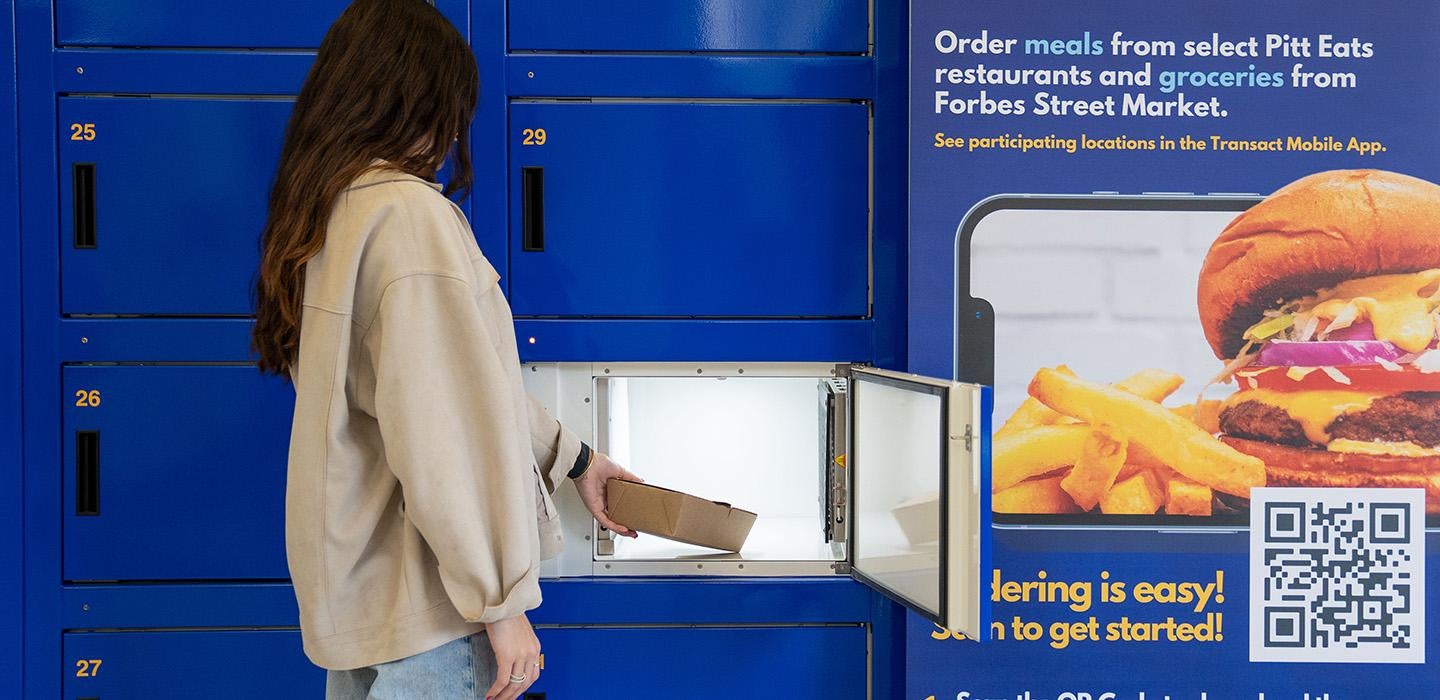 A person takes a to-go container out of a blue food locker
