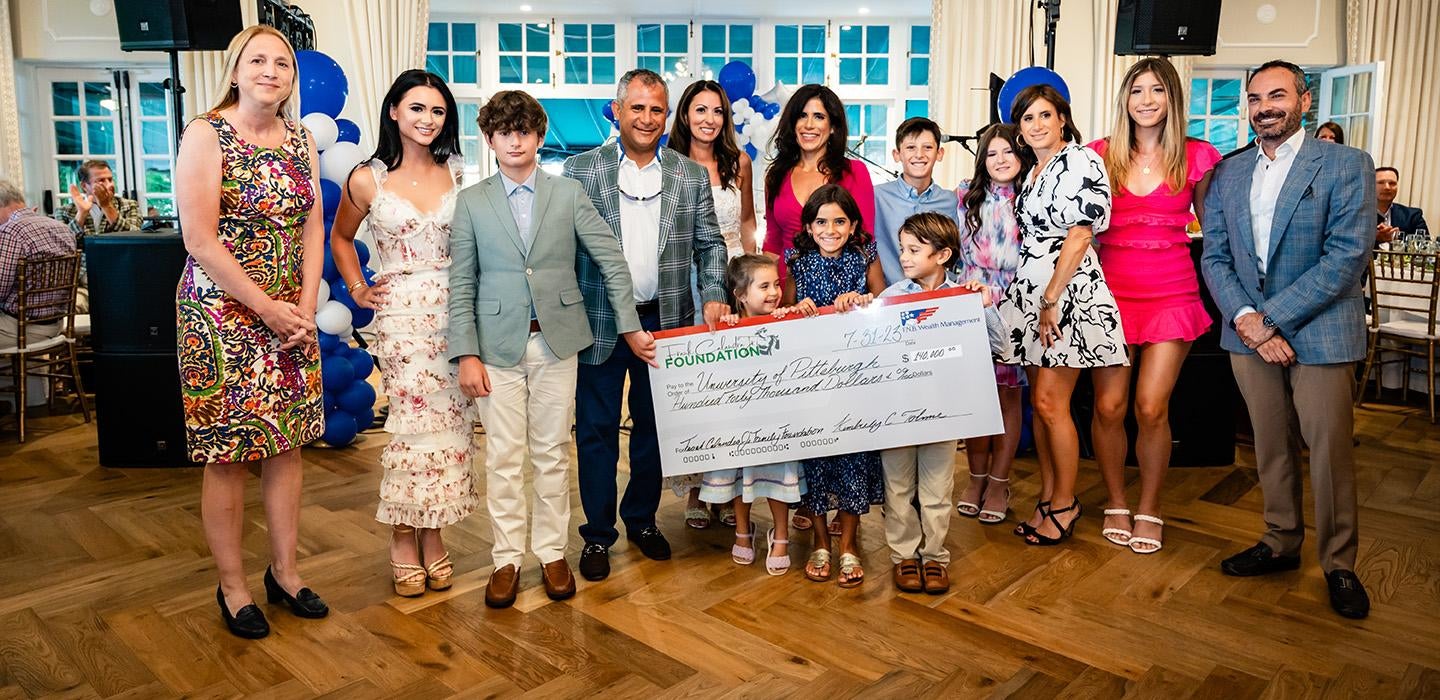 A group of people in formal wear hold a giant check