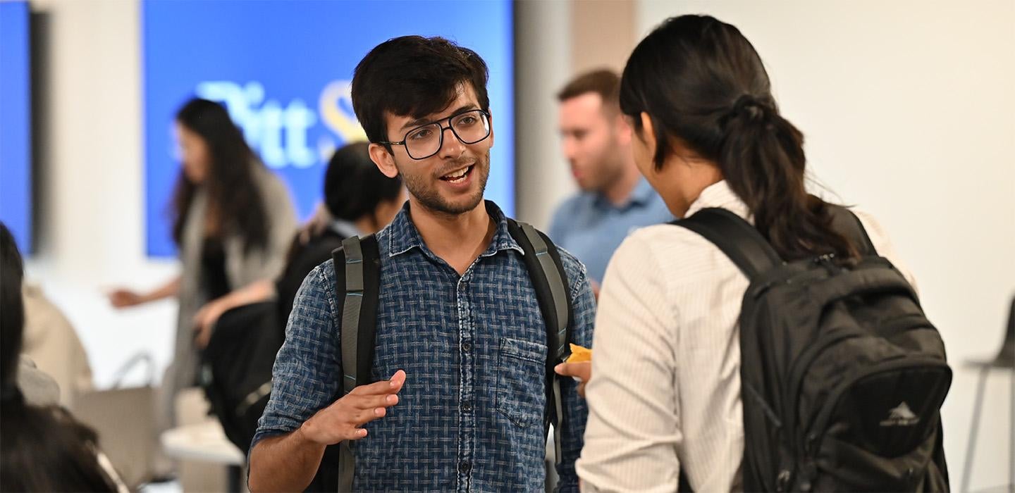 Two students talk at a School of Computing and Information event
