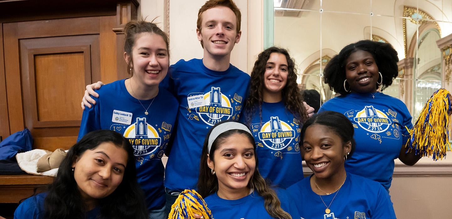 A group of students in blue Pitt Day of Giving shirts smile