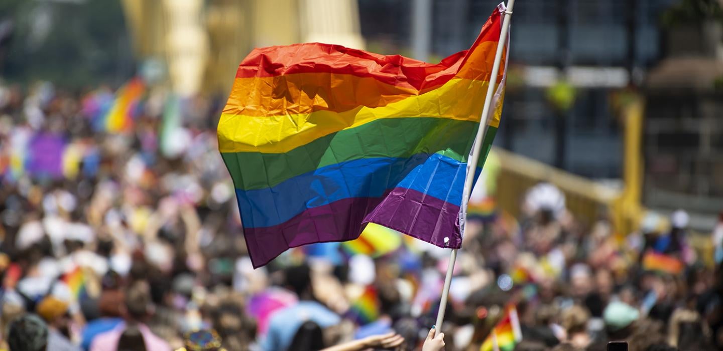 A pride march with a rainbow flag flying