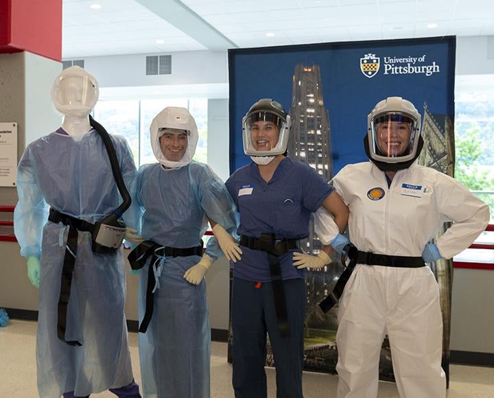 Scientists posing in uniforms smiling, arms around one another