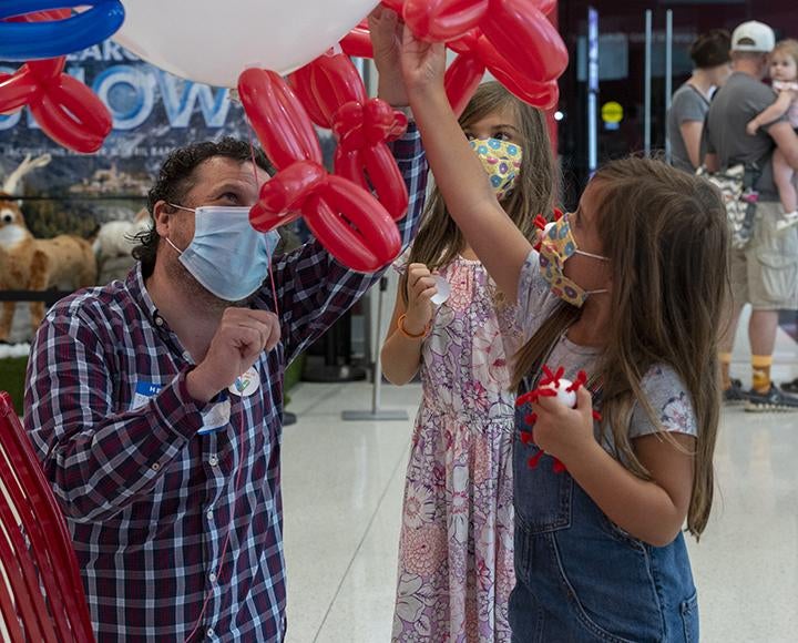 Children sticking red balloons to a larger white balloon