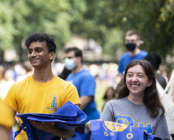 Vijay Cherupally, left, and Kami Olexik, right, pass out reusable shopping bags at the Student Activity Fair