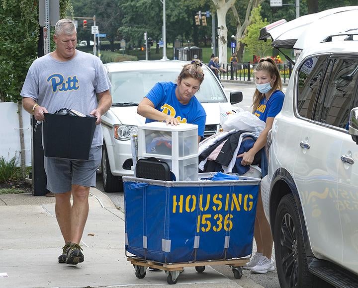 Pitt student loading blue moving cart with parents