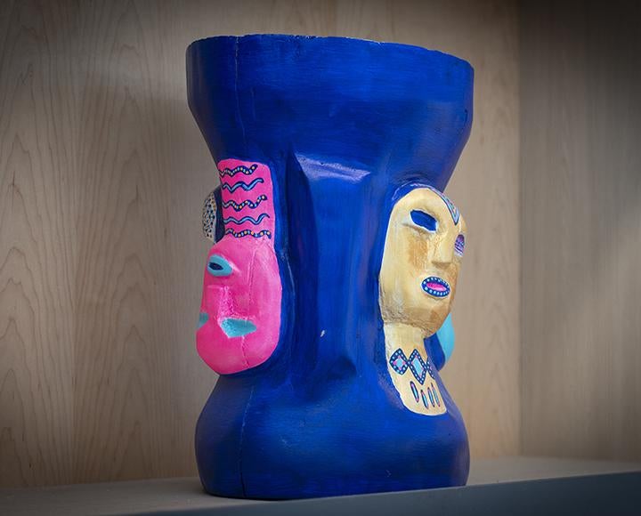 Blue sculpture with pink and yellow faces on it 