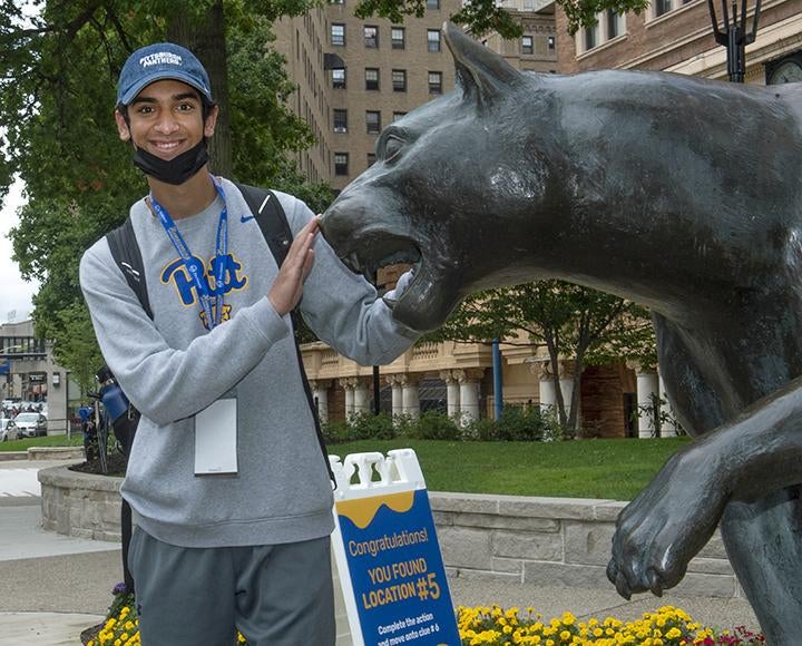 Man with Pitt sweater posing next to panther statue