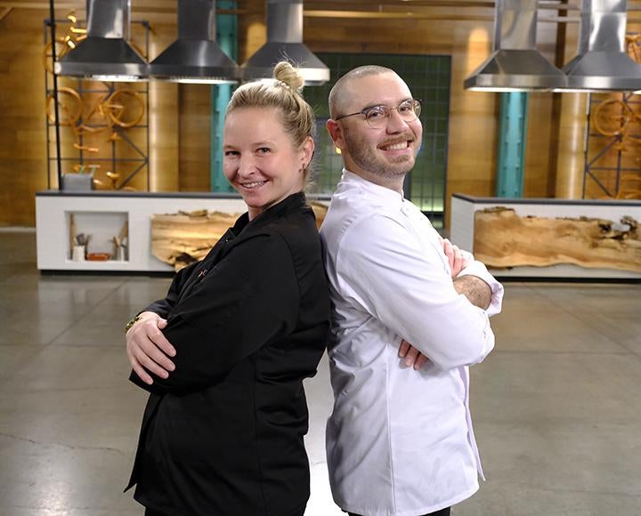 Brett Bankson posed back to back with another chef on Top Chef set