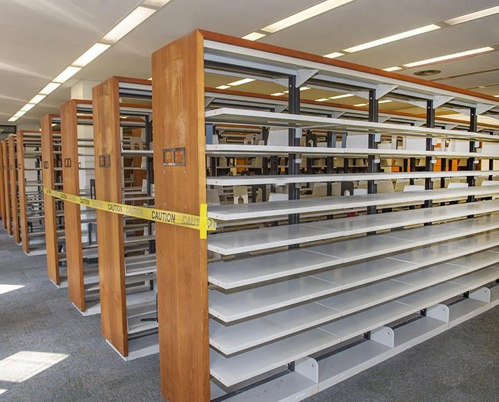 Hillman Library empty bookshelves blacked off with yellow caution tape