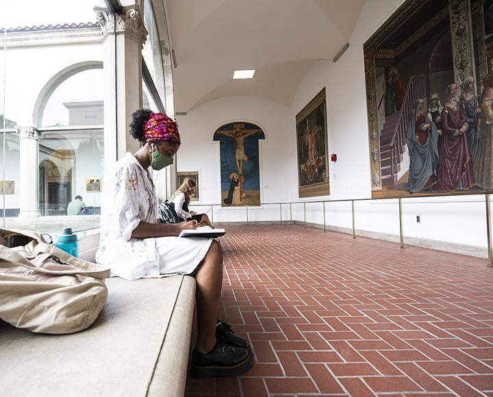 Student studying on campus with face mask on bench