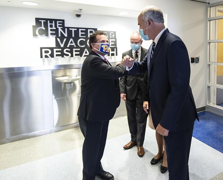 Bob Casey and Paul Duprex greeting each other in the Center for Vaccine Research