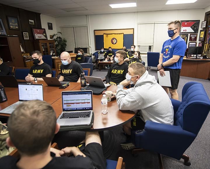 ROTC Army members gathered at a table with laptops and face masks