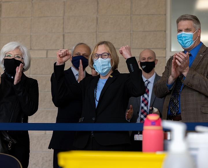 People wearing masks while cheering and clapping at vaccine clinic