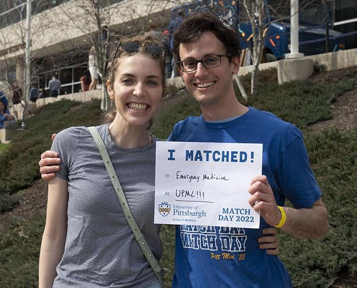 Two people posing together with Match Day results 