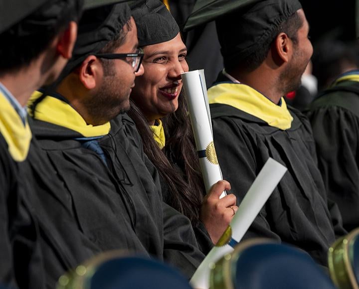 Graduating students smiling with diplomas in hand