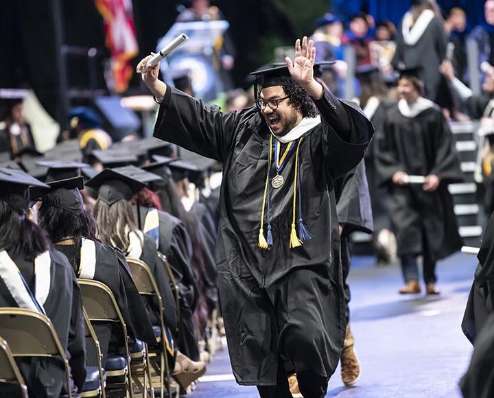 Graduating student walking down the isle cheering with hands in the air