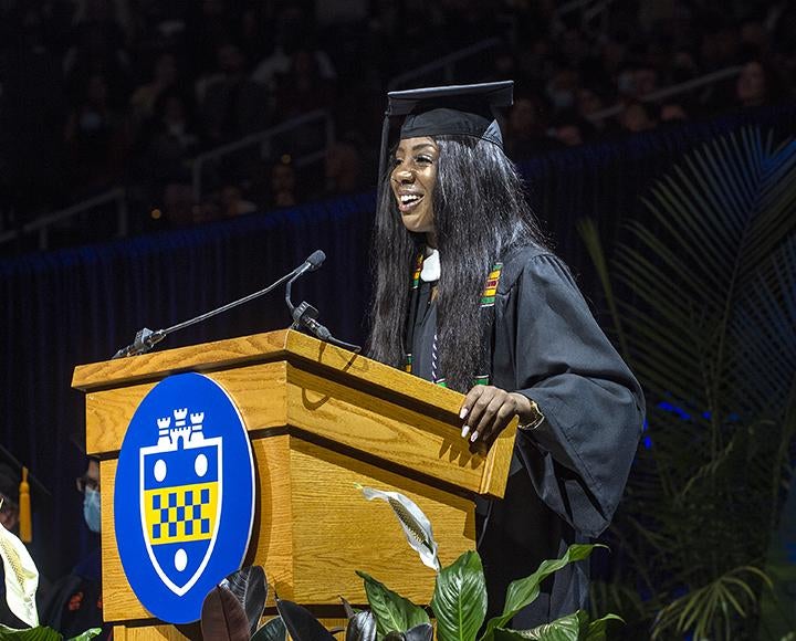 Gabriella Ogude in cap and gown speaking at podium during ceremony.