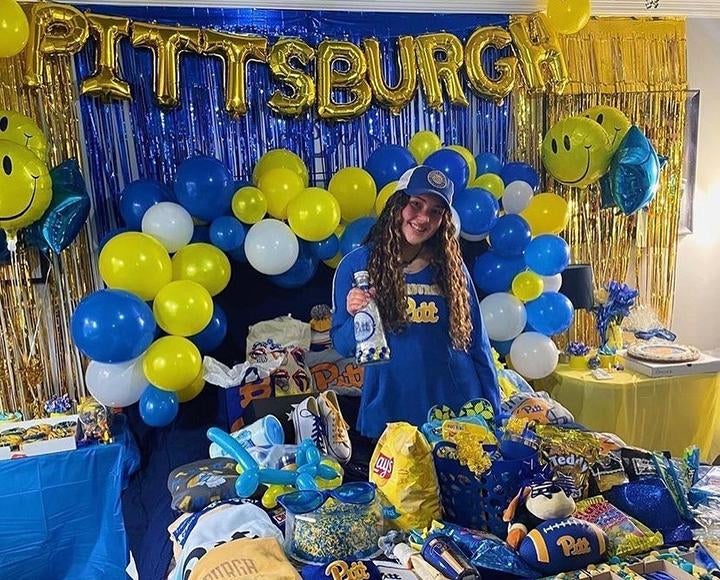 Girl with Pitt swag surrounded by blue and gold Pitt decorations and merchandise