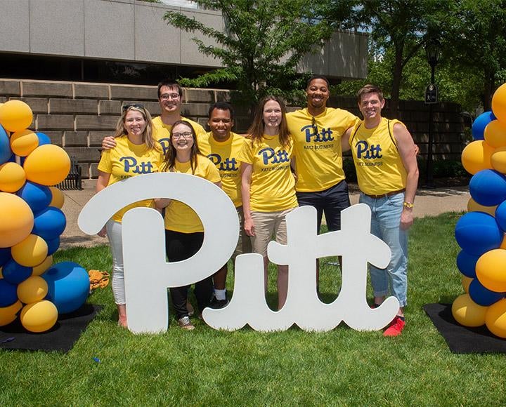 7 Pitt Business staffers in front of a Pitt sign