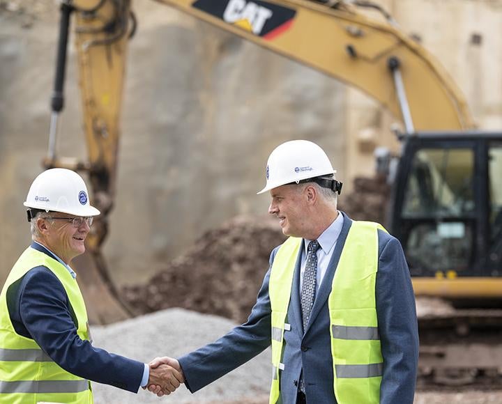 two men in construction vests and hats shaking hands