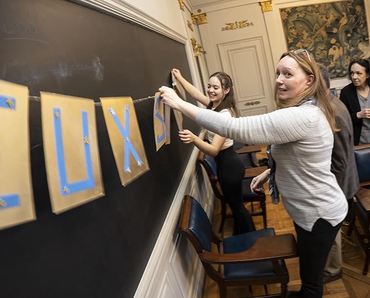 a mother and daughter hanging a banner on a chalk board