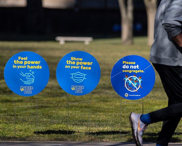 Blue circular yard signs promote mask-wearing and hand-washing