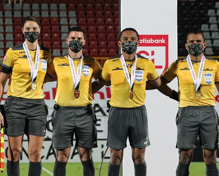 Four people in yellow FIFA jerseys pose with medals