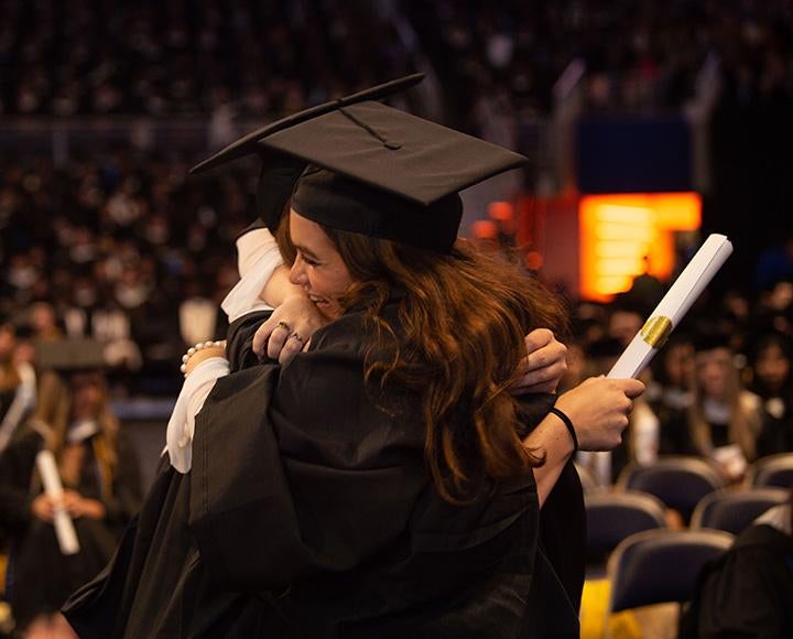 Two people in graduation robes hug