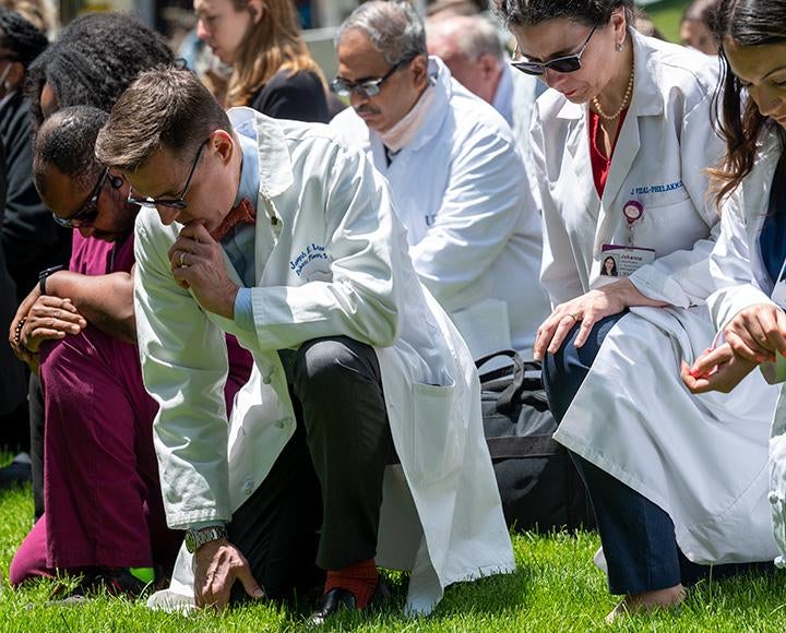 People in white coats kneel in the grass