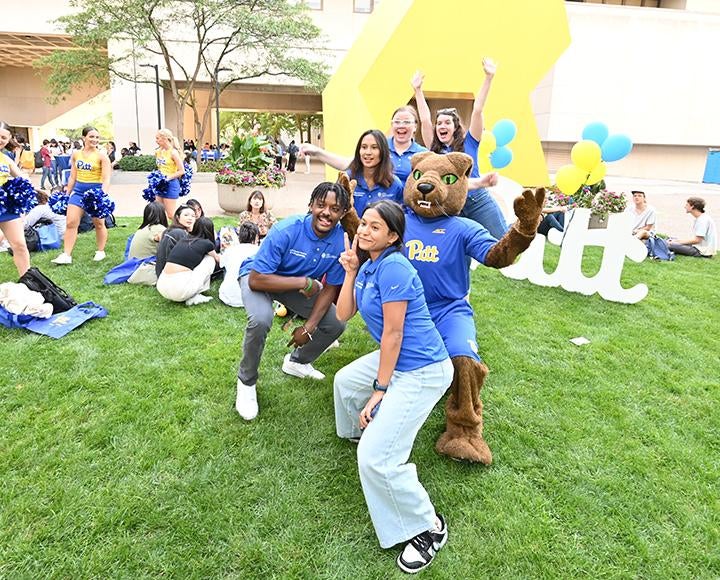 people dressed in blue and gold pose with Roc