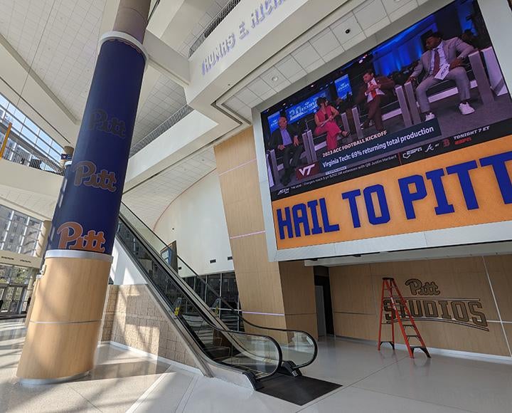 A screen near an escalator in the Petersen Events Center
