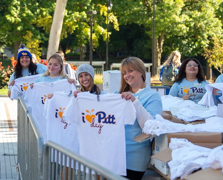 People hold up I Heart Pitt Day shirts in a line