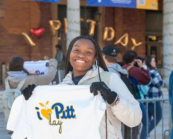 A person poses with a white shirt that reads I Heart Pitt Day