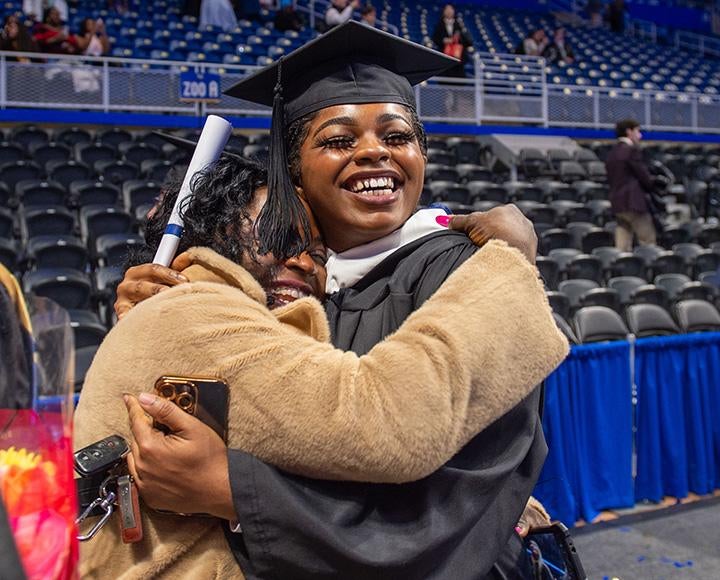 A graduate hugs their mother