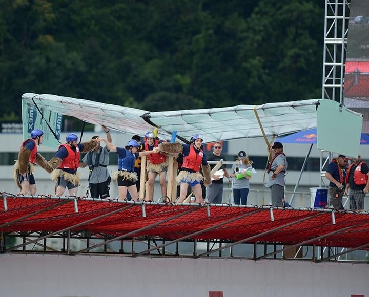 People in life jackets stand with their glider at the edge of a platform