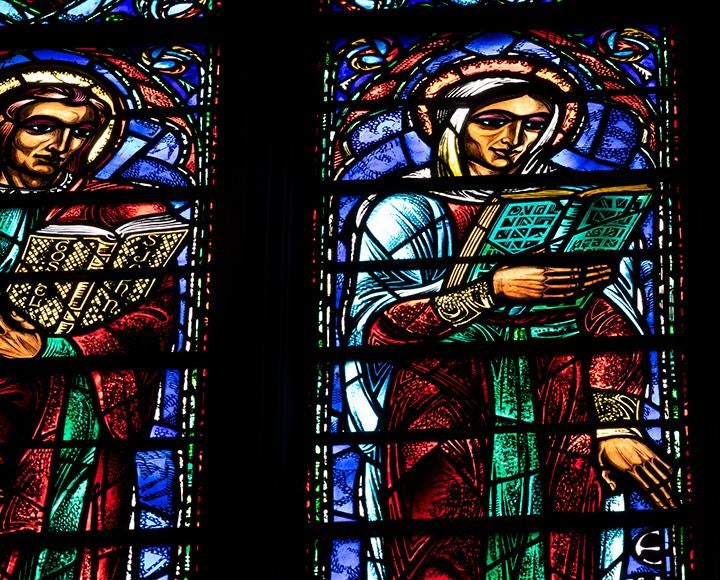 Two figures read books in stained-glass windows