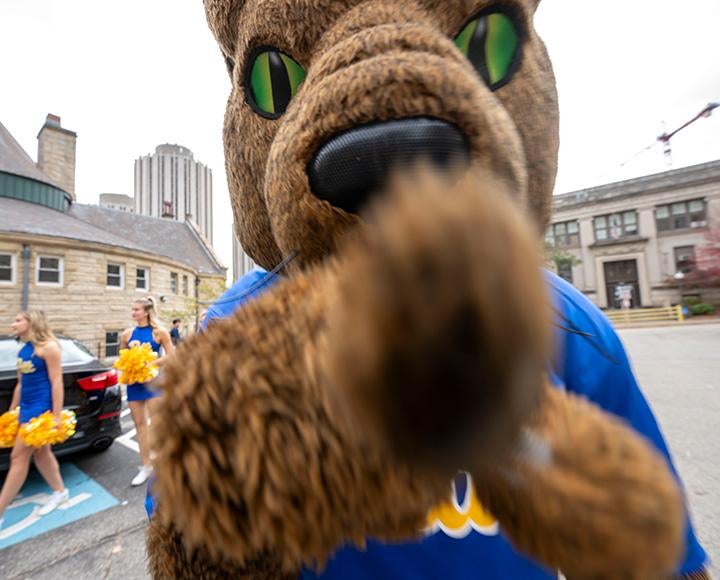 A panther mascot points into a camera