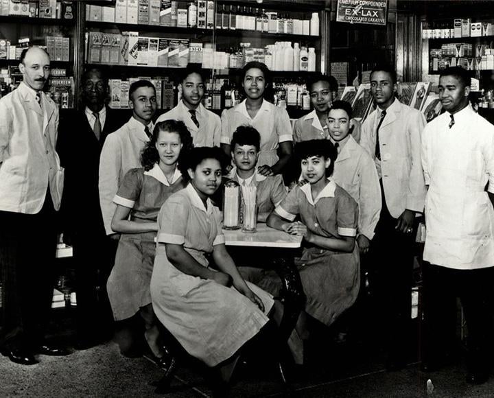 A black and white photo of staffers in a pharmacy