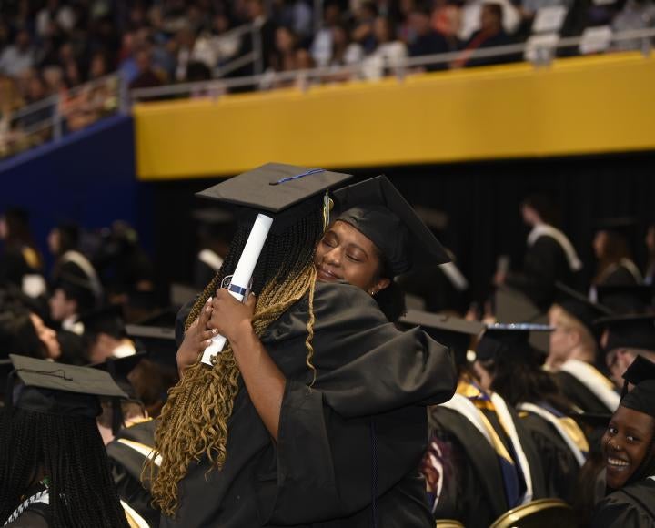Two graduates hug in the Petersen Events Center